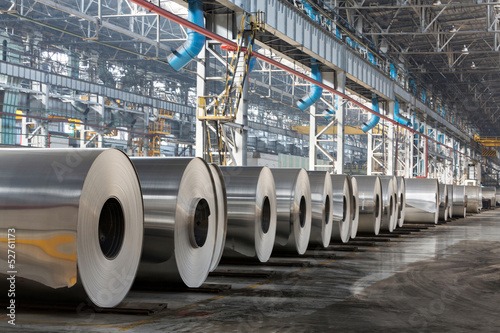 Row of rolls of aluminum lie in production shop of plant. photo