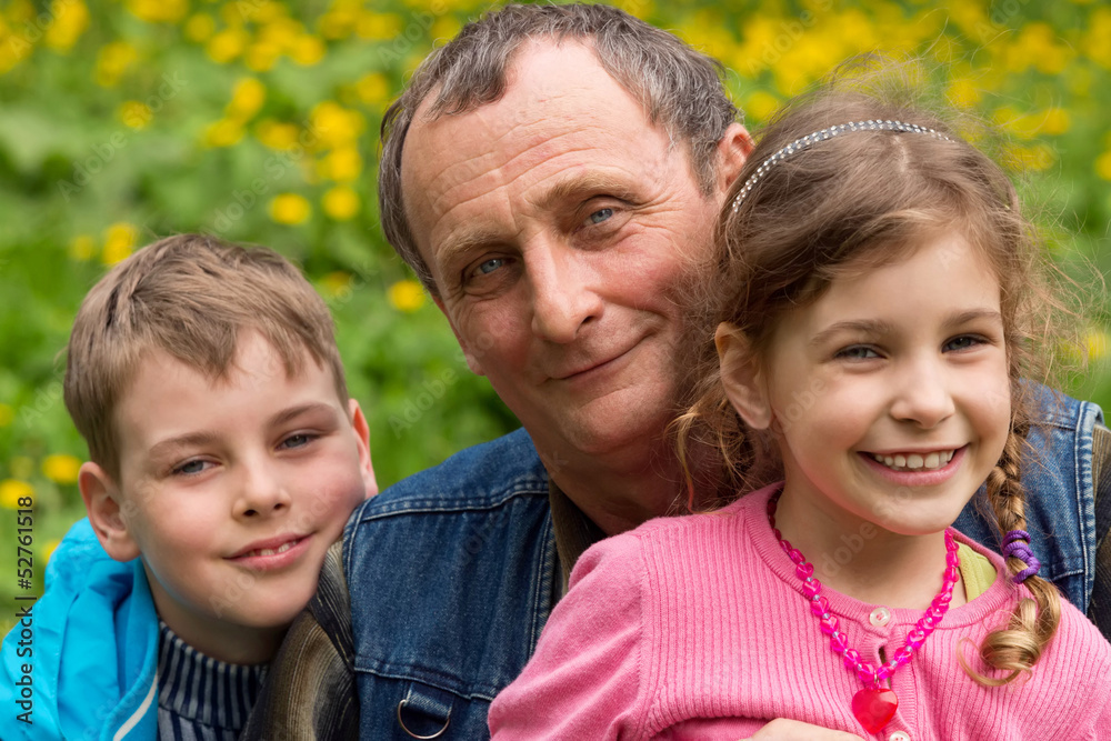 Fototapeta premium Grandfather, granddaughter and grandson smiling in nature.
