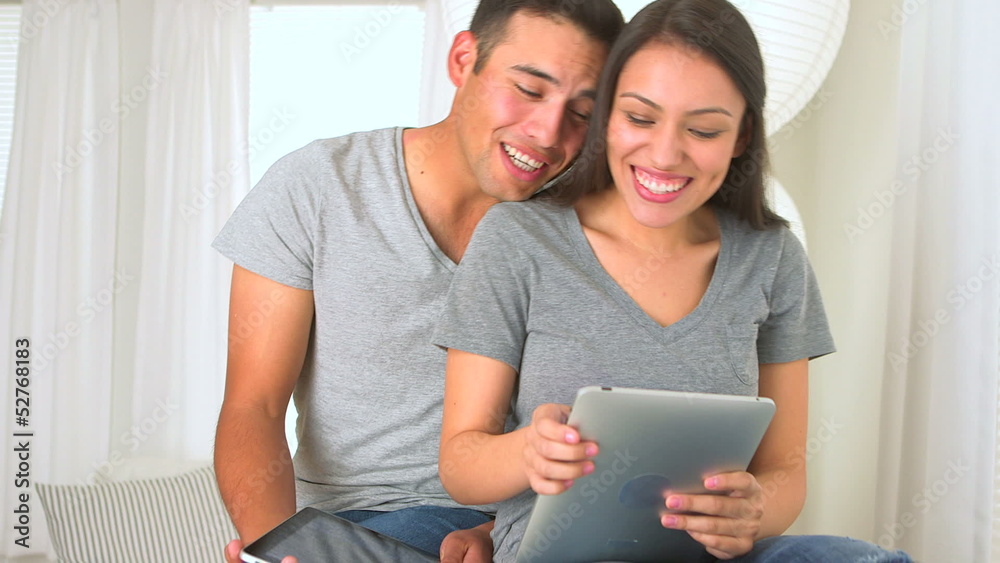 Happy Hispanic couple using their tablets Happy Hispanic couple using their tablets