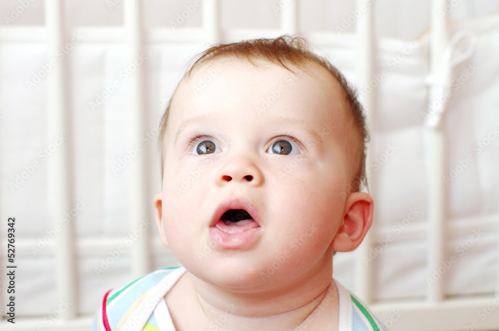 surprised baby against white bed