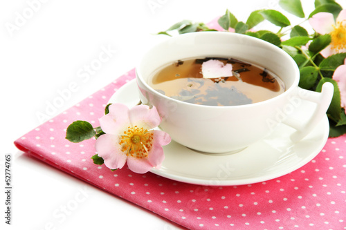 Cup of herbal tea with hip rose flowers, isolated on white