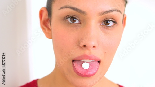 Smiling Mexican woman taking a pill photo