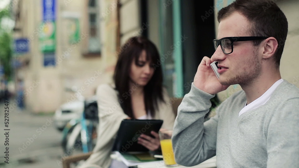 Young man talking on cell phone in cafe, steadicam shot Young man talking on cell phone in cafe, steadicam shot
