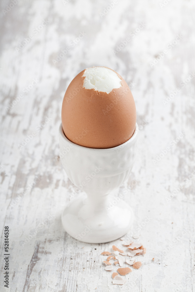 Boiled egg in an eggcup on wooden background.