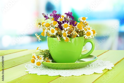 Fototapeta Naklejka Na Ścianę i Meble -  Bouquet of chamomile flowers in cup, on bright background