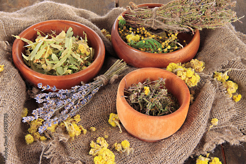 Medicinal Herbs in wooden bowls on bagging close-up