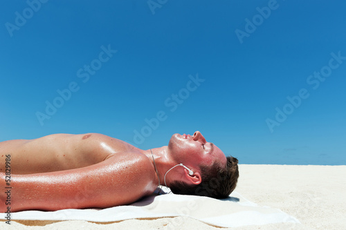 Man sunbathes and listens to music on the beautiful beach