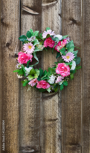 Floral wreath hanging on rustic wooden fence