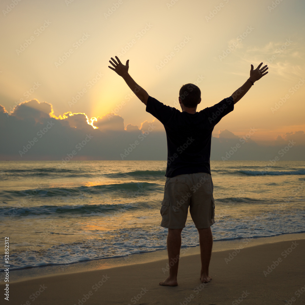 Fototapeta premium Man with his hands up on the dawn on the beach