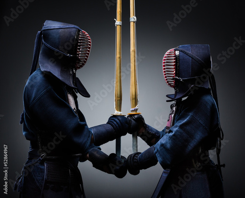 Two kendo fighters with shinai opposite each other photo