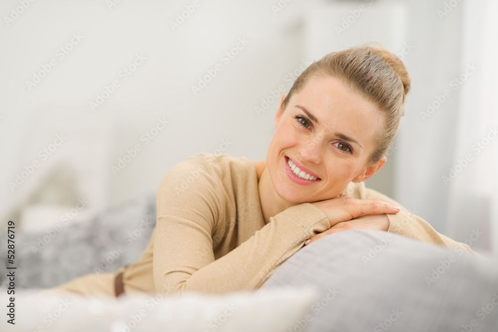 Smiling young woman sitting on couch in living room Smiling young woman sitting on couch in living room