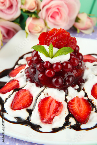 Tasty jelly dessert with fresh berries, on pink roses