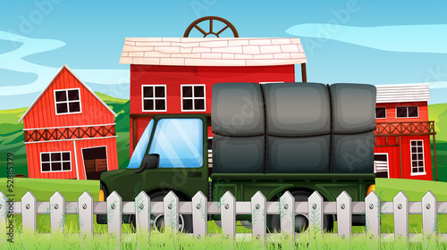 A green cargo in front of a barn inside the fence