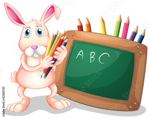 A bunny with coloring pens beside a blackboard