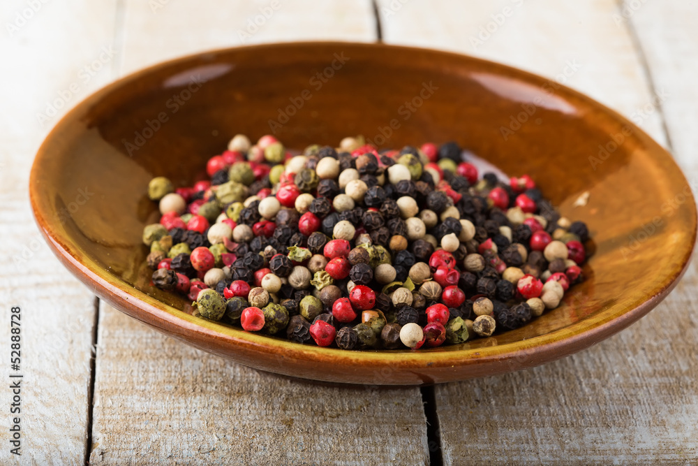 Mixed pepper on plate on wooden background Mixed pepper on plate on wooden background