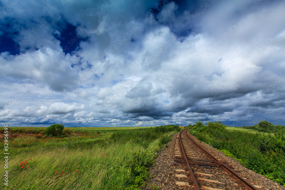 Obraz premium Scenic railroad in rural area in summer with storm clouds