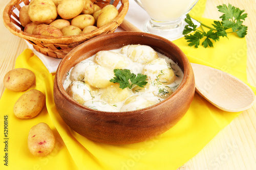 Tender young potatoes with sour cream and herbs in wooden bowl