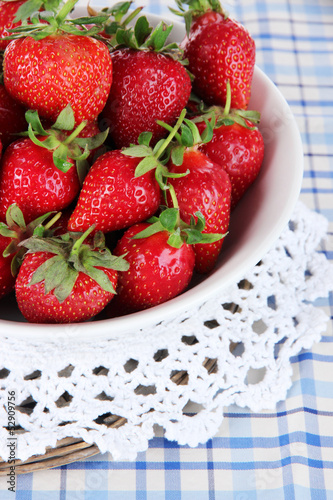 Strawberries in plate on wicker stand on napkin close-up