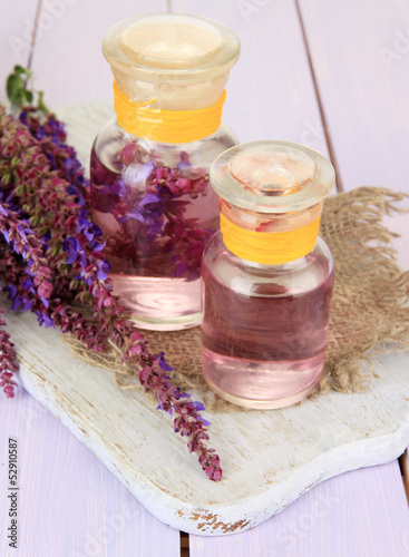 Medicine bottles with salvia flowers on purple wooden