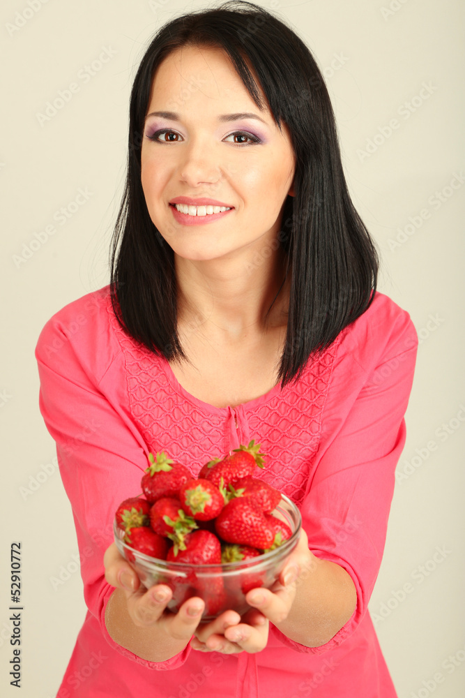Beautiful young woman with strawberries on grey background Beautiful young woman with strawberries on grey background