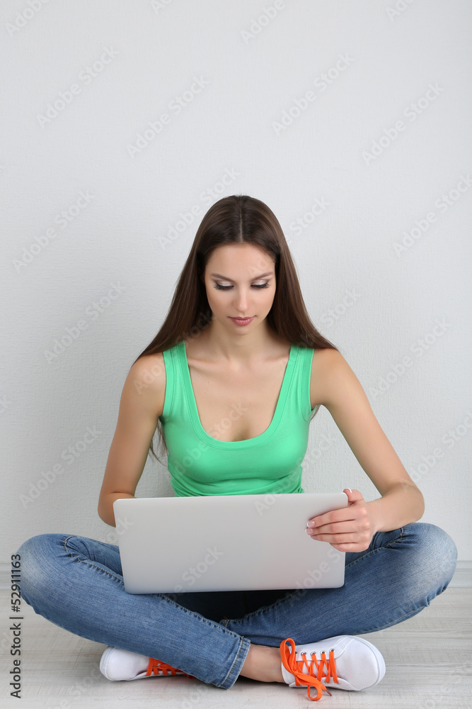 Beautiful young woman sitting with laptop in room Beautiful young woman sitting with laptop in room