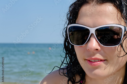 Woman in sunglasses posing at the sea