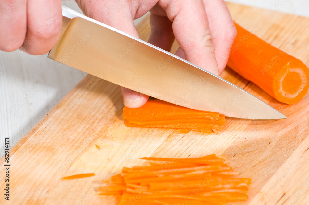 Chef cutting the carrot on a wooden board Chef cutting the carrot on a wooden board