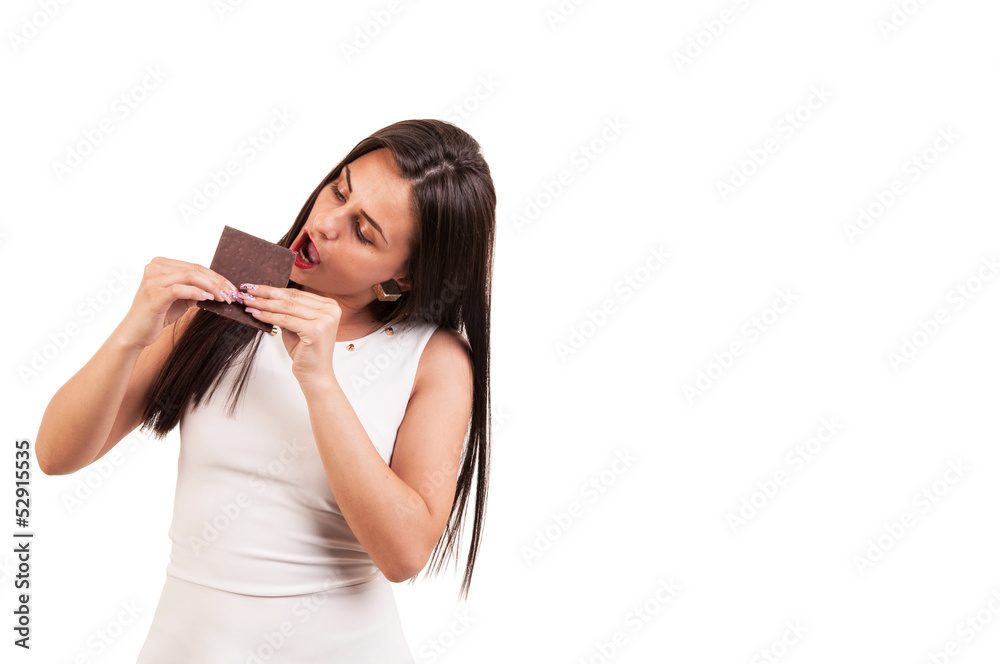 Young woman eating chocolate bar with lust on white background,