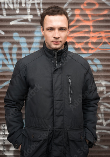 Caucasian man in black jacket with graffiti