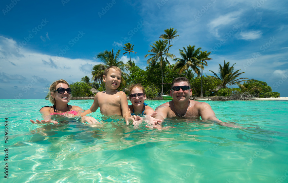 Family swims against the beautiful tropical island