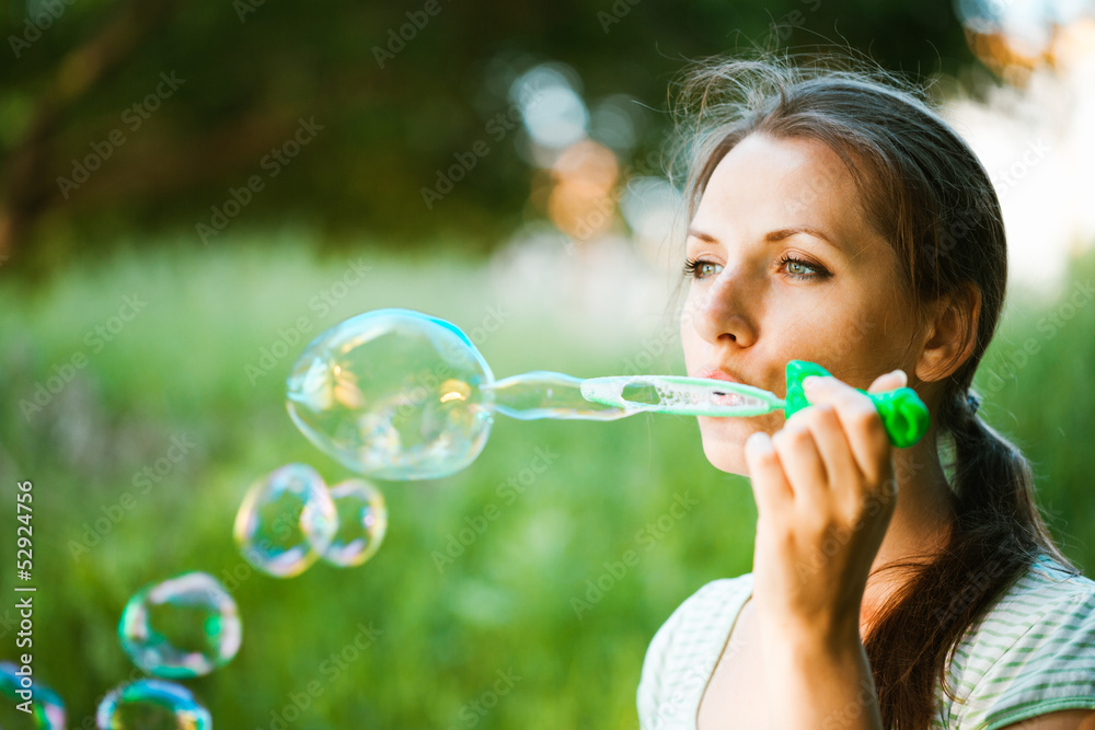 Girl blowing soap bubbles in the park