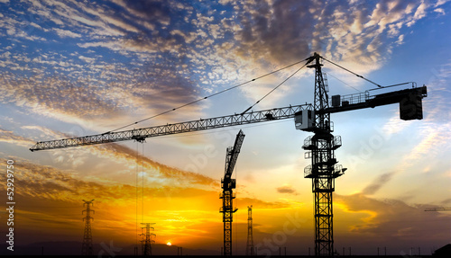 Industrial construction cranes and building silhouettes 