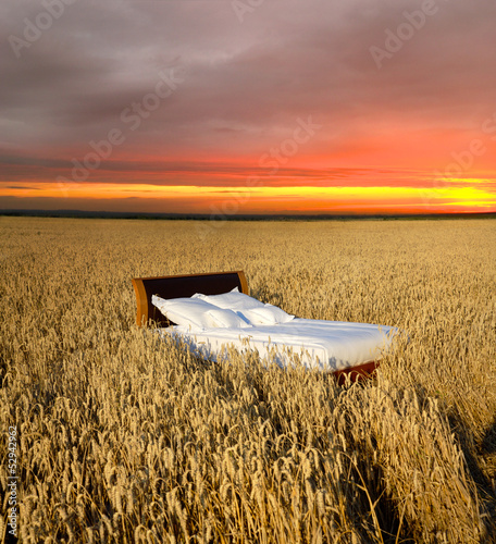 Fotografia bed in a grain field - concept of good sleep