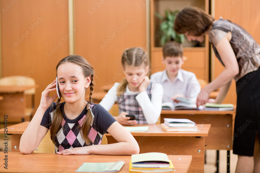 Primary school pupil using cell phone at lesson Primary school pupil using cell phone at lesson