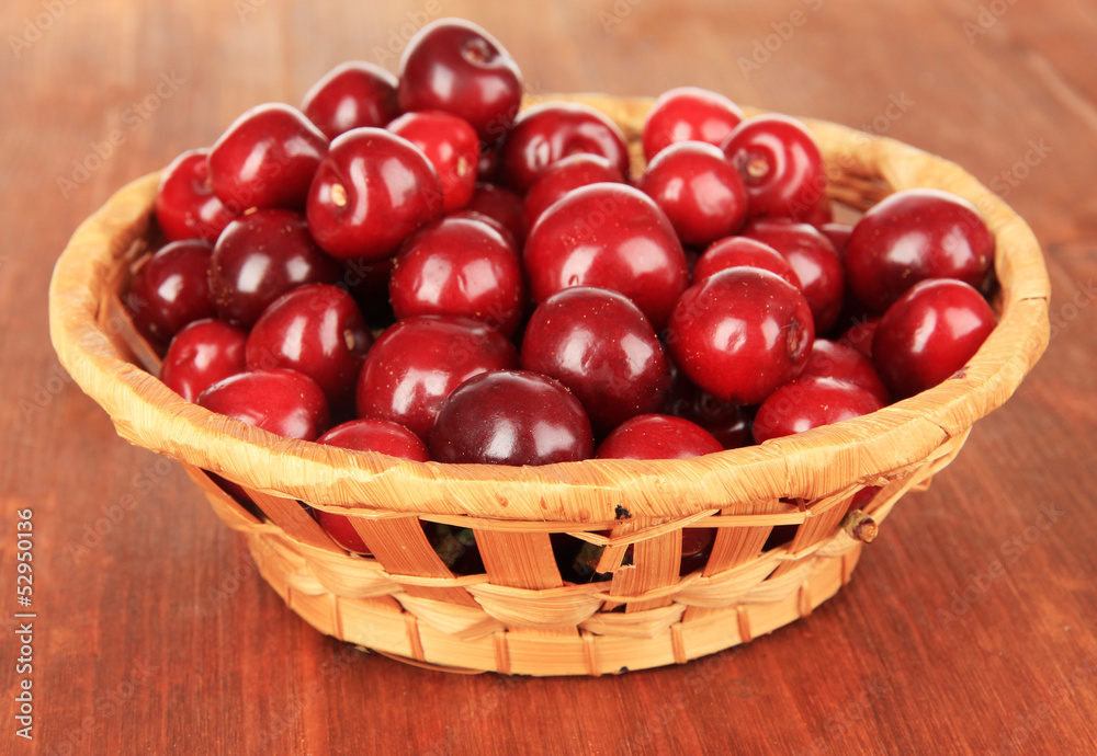 Cherry berries in wicker basket on wooden table close-up Cherry berries in wicker basket on wooden table close-up