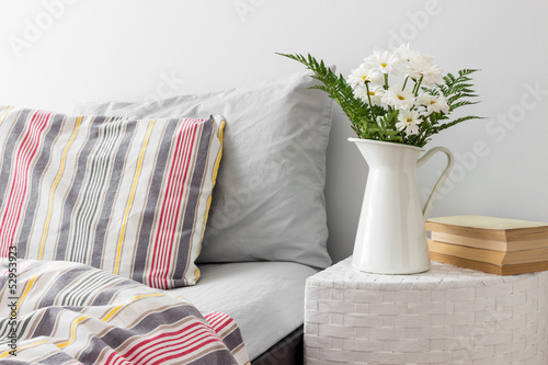 White flowers and books on a bedside table