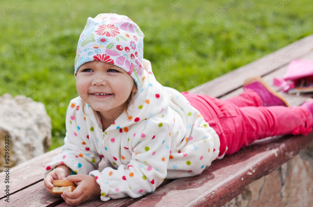 Happy child eating crackers lying on a bench Happy child eating crackers lying on a bench