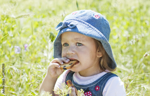 Cute baby eating crackers on green grass