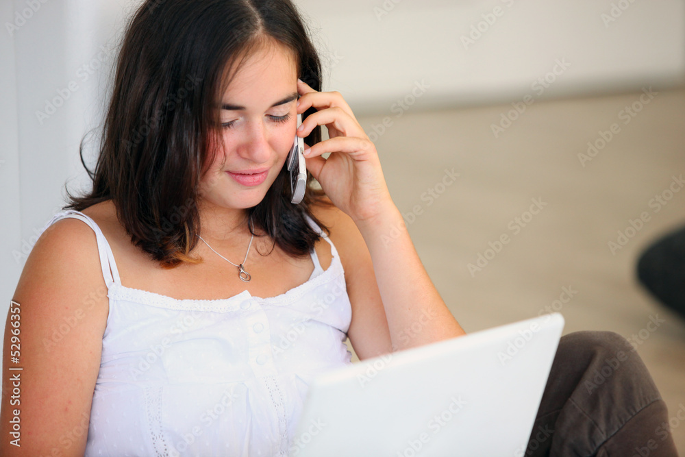female student working on laptop using cell phone female student working on laptop using cell phone