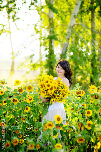 young woman on blooming sunflower field in summer