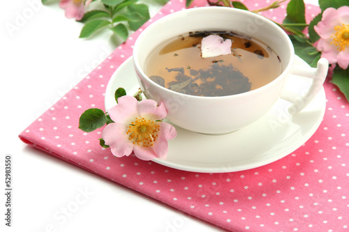 Cup of herbal tea with hip rose flowers, isolated on white