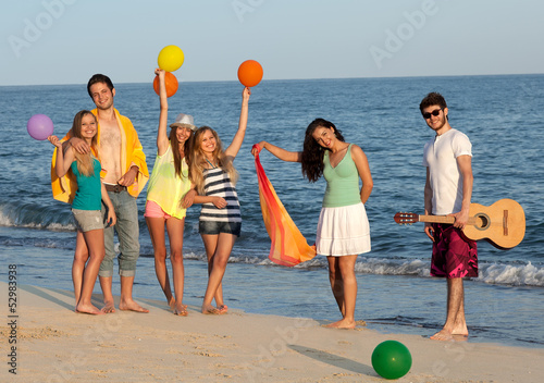 Group of young people enjoying beach party with guitar and ballo photo