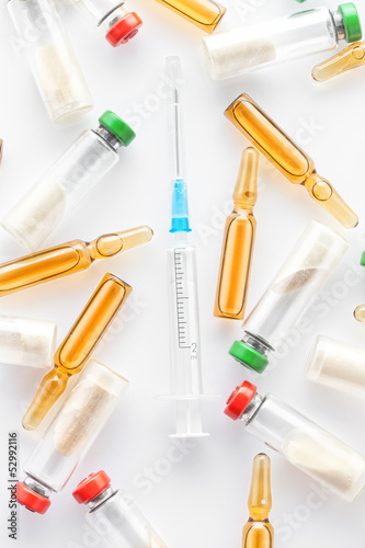 Close up view of syringe and different ampoules on white back