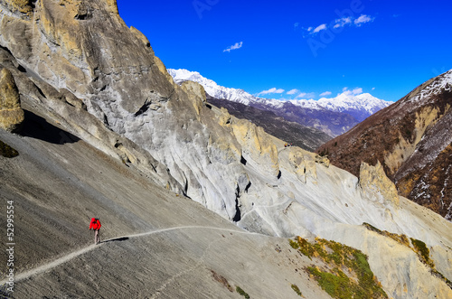 Trekker in red jacket in Himalayas mountains photo