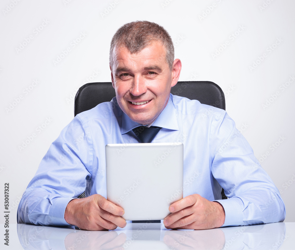 old business man at desk holds his tablet old business man at desk holds his tablet