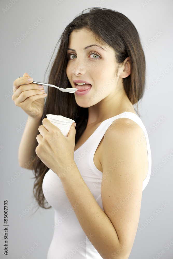 Happy gorgeous female model eating white yogurt being on a diet Happy gorgeous female model eating white yogurt being on a diet