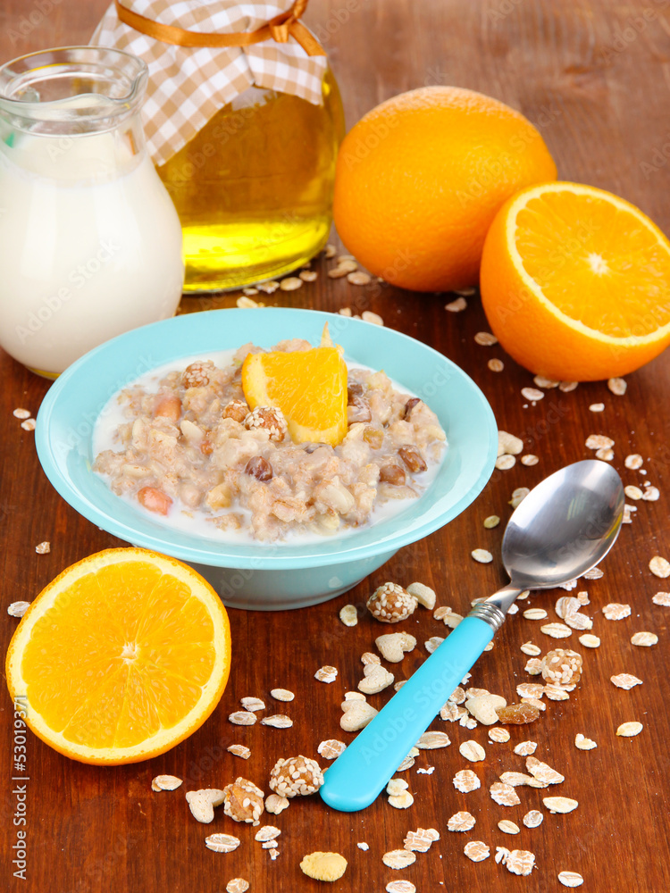 Useful oatmeal in bowl with fruit on wooden table close-up