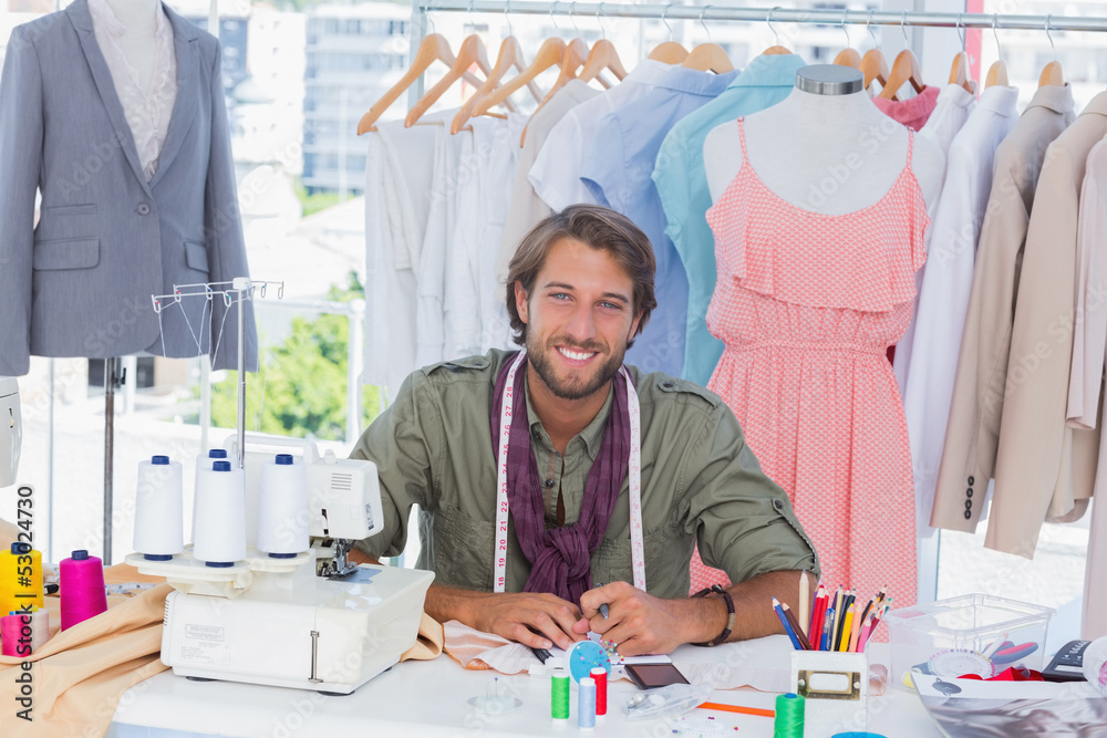 Smiling fashion designer sitting behind a desk Smiling fashion designer sitting behind a desk