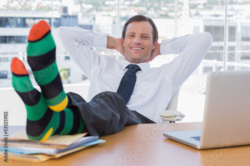 Smiling businessman relaxing with feet on his desk photo