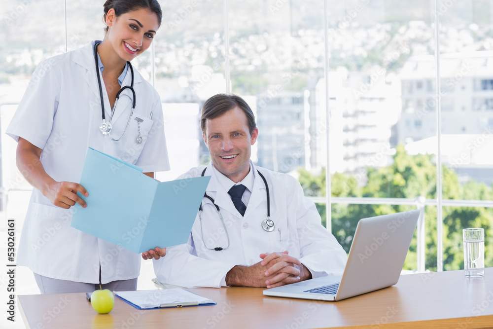 Pretty doctor showing a folder to a colleague Pretty doctor showing a folder to a colleague